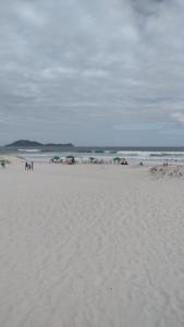 eine Gruppe von Menschen, die an einem Sandstrand stehen in der Unterkunft Apartamento dunas cabo frio in Cabo Frio