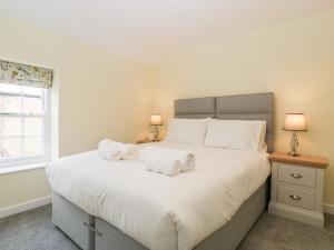 a bedroom with a large white bed with towels on it at Granary Cottage in Warminster