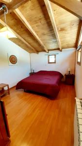 1 cama grande de color rojo en una habitación con suelo de madera en Hostel Los Coihues en San Carlos de Bariloche