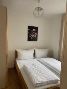 1 cama con sábanas blancas y una foto en la pared en Modern apartment with balcony near city center, en Viena