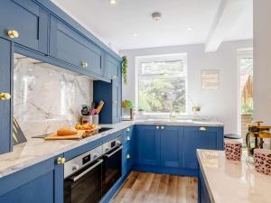a blue kitchen with white walls and wooden floors at Dawns House Cromford The Peaks in Cromford