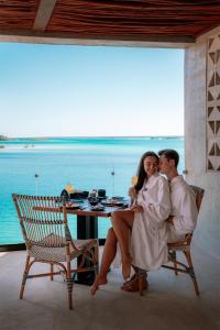 a man and woman sitting on a chair in front of a table at Hotel Amainah Bacalar Adults Only in Bacalar