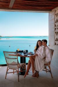 a man and woman sitting on a chair in front of a table at Hotel Amainah Bacalar in Bacalar