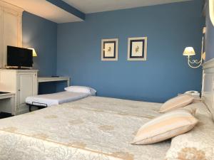 a blue bedroom with two beds and a tv at Hotel Leonor Mirón in Soria