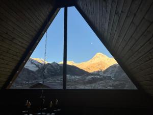 una ventana en una habitación con montañas en el fondo en Eco cottage Kazbegi, en Kazbegi