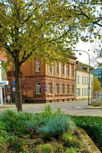 uma árvore em frente a um edifício com uma rua em Hotel Stadtvilla Laux em Merzig