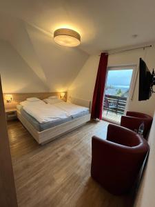 a bedroom with a bed and two chairs and a window at Hotel Clemens in Winterberg