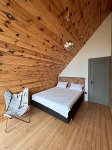 a bedroom with a wooden ceiling with a bed and a chair at Cabana Neagră in Beliş