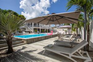 een parasol en een stoel naast een zwembad bij INDIGO Apartments & Suites - 'Adults Only' in Jan Thiel