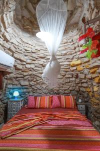 a bedroom with a bed in a stone wall at Piccolo Trullo Salentino in Marina di Pescoluse
