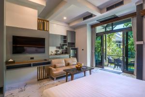 a bedroom with a bed and a couch and a tv at Loy Chalet in Klong Muang Beach