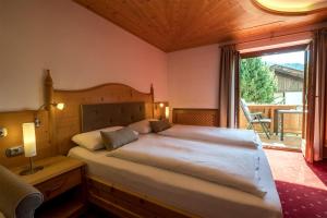 a bedroom with a large bed and a large window at Garni Alba Bed & Breakfast in Ortisei