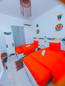 a bedroom with two red beds and a chandelier at Lawanda Nubian House in Aswan