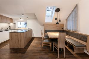 una cucina e una sala da pranzo con tavolo e sedie in legno di Alpenrose Alpine Living a Selva