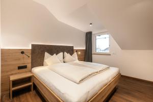 una camera da letto con un grande letto con lenzuola bianche e una finestra di Alpenrose Alpine Living a Selva