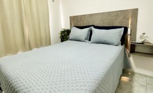 - une chambre avec un grand lit blanc et des oreillers bleus dans l'établissement Fortal Flat, à Fortaleza