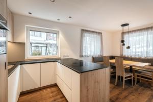 a kitchen with white cabinets and a table with chairs at Alpenrose Alpine Living in Selva +26 photos