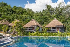 a row of cottages with a pool and trees at Loy Chalet in Klong Muang Beach