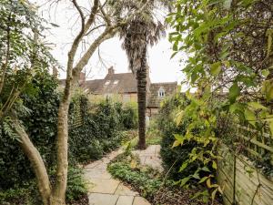 einen Gartenweg mit Bäumen und ein Haus im Hintergrund in der Unterkunft Foxden in Sherborne