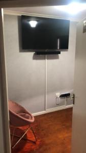 a room with a chair and a television on a wall at St Pete Private Suites in Newton Park