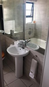 a bathroom with a sink and a mirror and a tub at St Pete Private Suites in Newton Park