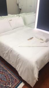 Una cama blanca con sábanas blancas y almohadas. en St Pete Private Suites en Newton Park