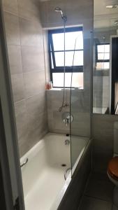 a bathroom with a bath tub with a shower at St Pete Private Suites in Newton Park
