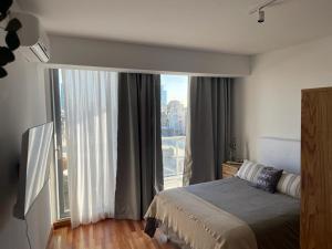 een slaapkamer met een bed en een groot raam bij Moderno departamento Palermo vista La Rural in Buenos Aires +44 foto's