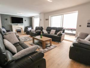 a living room with leather furniture and a fireplace at The Beach House in Prestatyn