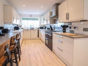 a large kitchen with white cabinets and wooden floors at The Beach House in Prestatyn