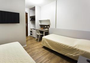 a hotel room with two beds and a desk at Tropikalya Prime Hotel in Balneário Camboriú