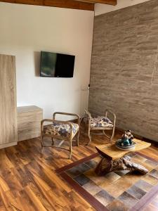 sala de estar con 2 sillas, mesa y TV en Altavista comodidad modernidad y seguridad, en Ranco