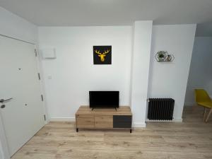 uma sala de estar com televisão numa parede branca em Industrial -Apartamentos Birdie- em Albacete