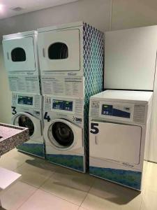 Duas máquinas de lavar roupa e uma máquina de lavar e secar roupa num quarto em Estúdio Brás - Comercial em São Paulo