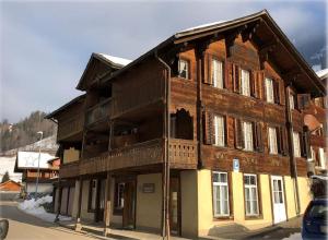 un grand bâtiment en bois sur le côté d'une rue dans l'établissement Hotel Bären Lodge, à Kiental