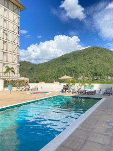 una piscina en un hotel con una montaña en el fondo en Estudio Em Itaipava - Granja Brasil - Flat Luxo - Com Piscina Aquecida, en Itaipava