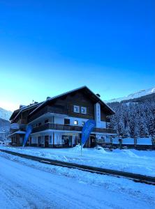 ein großes Gebäude im Schnee neben einer Straße in der Unterkunft Hotel Genzianella in Santa Caterina Valfurva