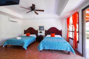 a bedroom with two beds and a ceiling fan at Beach Break Resort in Jacó