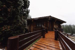 a log cabin with a wooden walkway leading to it at Котедж Яблуниця in Yablunytsya