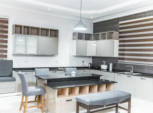 a large kitchen with white cabinets and blue chairs at Beautiful home with private rooms in Pantang