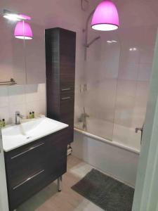 een badkamer met een wastafel, een bad en roze verlichting bij Charmant appartement au calme in Bourg-en-Bresse