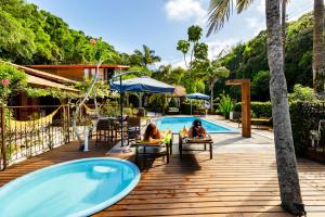 two people sitting on a deck next to a swimming pool at Estalagem Don Pablo in Bombinhas
