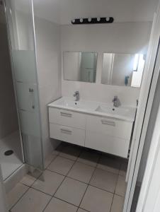 - une salle de bains blanche avec deux lavabos et une douche dans l'établissement Au cœur du village d' Argelès-sur-Mer, à Argelès-sur-Mer