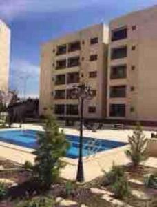 ein großes Gebäude mit einem Pool vor einem Gebäude in der Unterkunft Cozy 2 BR apartment, with pool and big yard in Amman