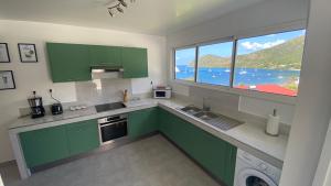 a kitchen with green cabinets and a large window at Appartement vue mer Chez Ti Louis - Grande Anse in Les Anses-dʼArlets