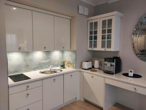 a kitchen with white cabinets and a sink and a microwave at Patio Glamour in Koszalin