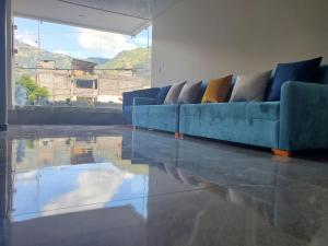 a living room with a blue couch and a reflection in the floor at Xperience Hotel Ec in Baños