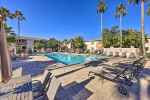 a swimming pool with lounge chairs and palm trees at Phoenix Condo with Pool and Hot Tub - Dog Friendly! in Phoenix