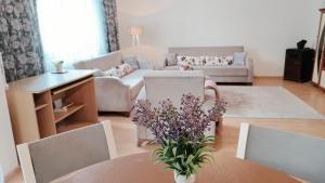 una sala de estar con una mesa con un jarrón de flores en City Park Apartments, en Pristina