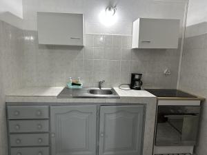 eine Küche mit einem Waschbecken und weißen Schränken in der Unterkunft Peyi Galante Évasion in Saint-Louis